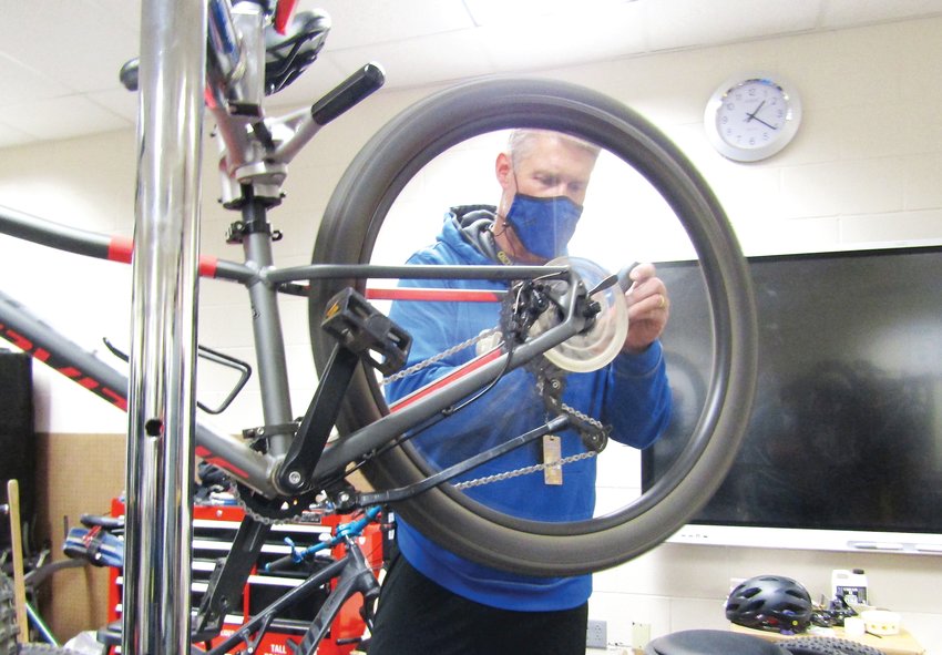 Teacher Brian Inman makes an adjustment to a bike.