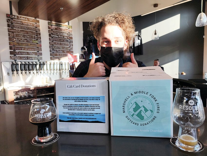 Resolute Brewery beer tender Jonny Eves behind two gift card collection boxes used to raise funds for victims of the Marshall and Middle Fork Fires.
