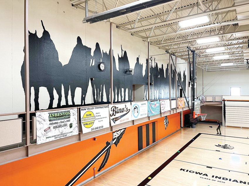 A large mural depicting Native Americans on horseback covers the upper west wall of the Kiowa Schools gym, with other imagery related to the Kiowa Indians mascot on the court-level wall.
