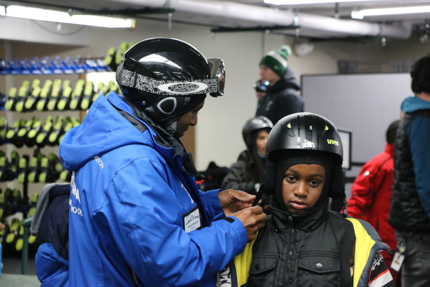 An instructor helps a student adjust his helmet before getting outside.