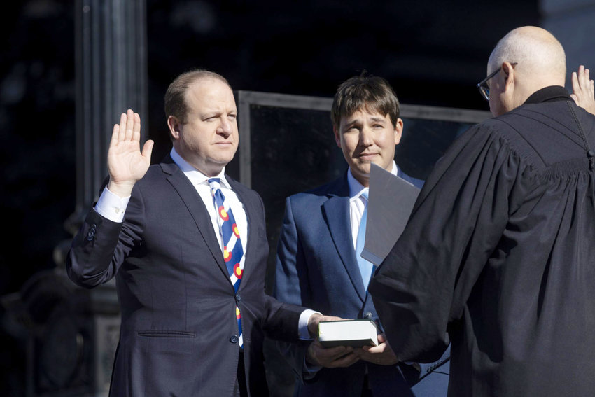 Gov. Jared Polis is being sworn in standing next to his husband, Marlon Reis, Tuesday, Jan. 10, 2023, at the Colorado State Capitol in Denver.