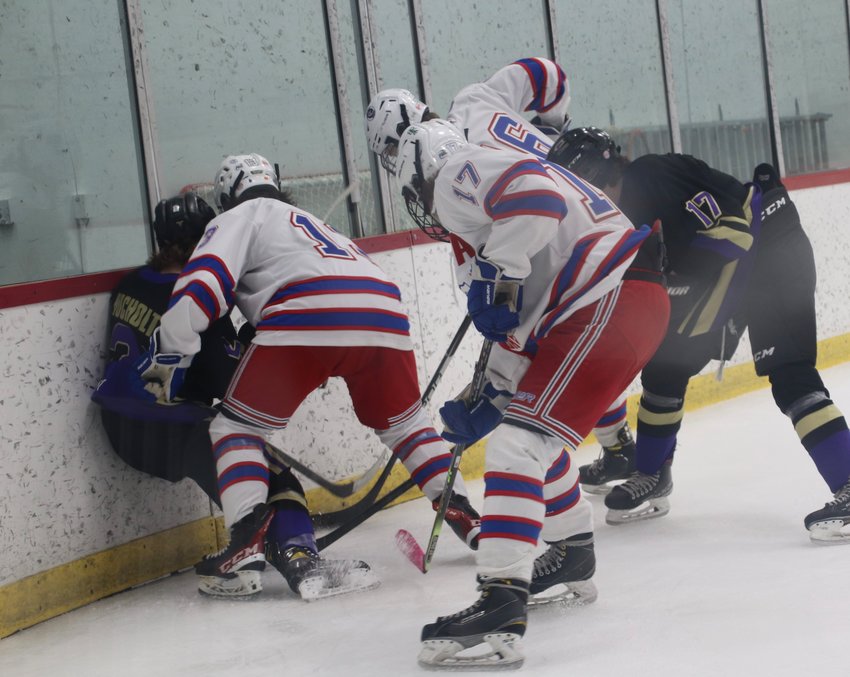 Cherry Creek players surround a Fort Collins player along the boards during a scramble for the puck. Creek edged Fort Collins 4-3 in a Jan 21 game.