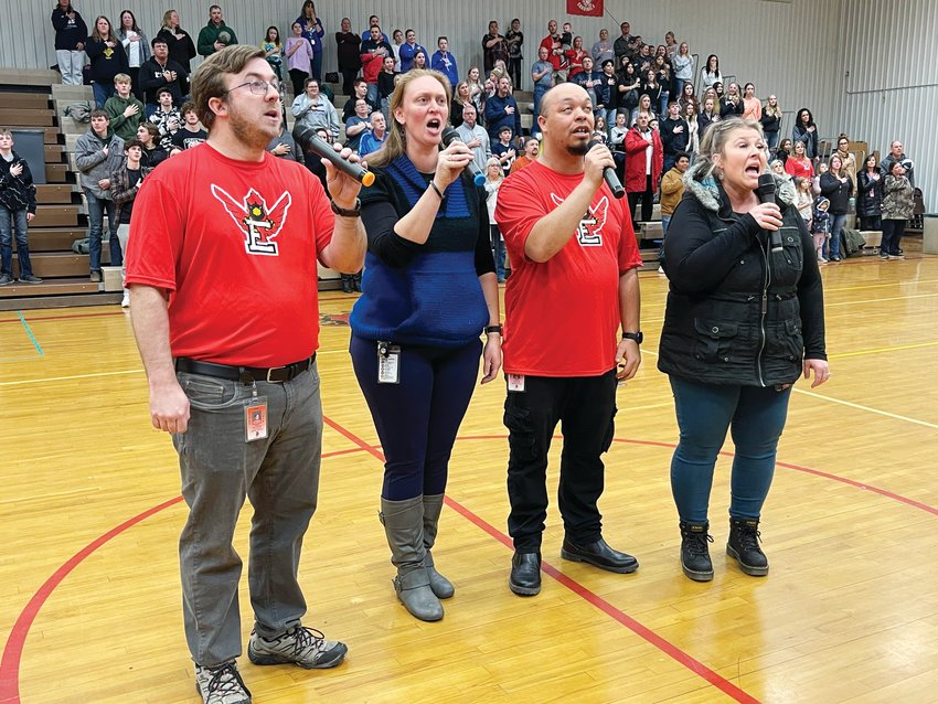 Staff and volunteers sing the national anthem ahead of the unified basketball game.