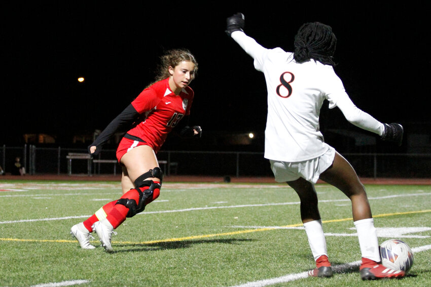 Kaylee Parrington (13) defends Erie's Nonzo Uwalaka (8) as she tries to cross it into the goal area. Erie defeated Brighton 3-0 in a league game in Brighton March 30.