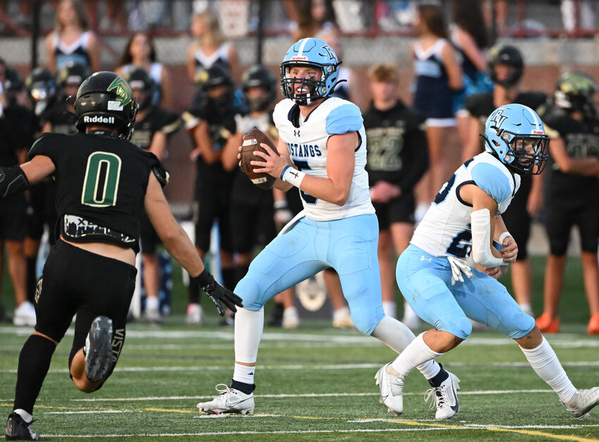 Ralston Valley QB Logan Madden (5) turns from the fake handoff to look for an open receiver as Mountain Vista defenders close in.