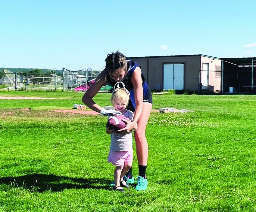 London Machado teaches the next generation of girls' flag football players how to throw a football.