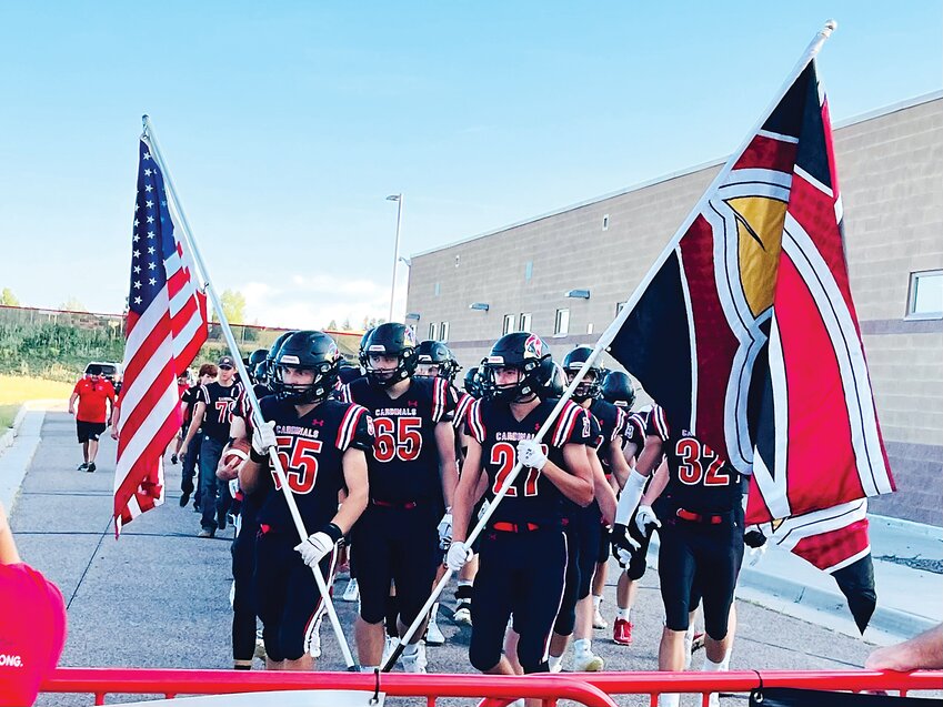 The Elizabeth Cardinals football team carries the American flag and the Cardinals flag into the stadium for their home game against Burlington on Sept. 1.