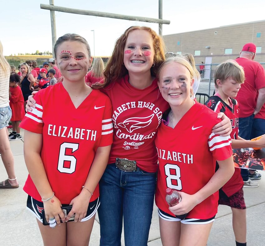 Three Elizabeth High School student athletes smile before the football game against Burlington on Sept. 1. From left are Jayden Quinton, Cora Lave and Emalee Guhl. Quinton and Guhl play on the EHS flag football team; Lave is on the EHS softball team.