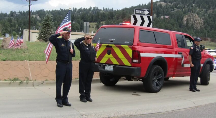 From left, Marty Lake, Kristy Tolan and Ed Mills with Evergreen Fire/Rescue stand at attention as the funeral procession for Major Toby Lewis went through the roundabout in Marshdale on its way to Evergreen Memorial Park.