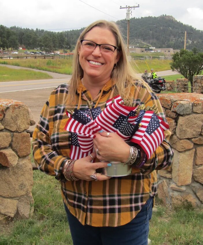 Debbie Stewart with Aspen Ridge Church distributes flags to the people lining North Turkey Creek Road and Highway 73. Church leaders went to stores in Evergreen and Conifer and found 275 flags to hand out and to place along the road.
