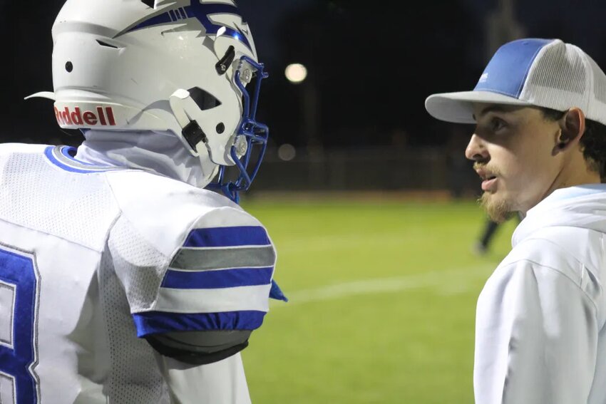 Fort Lupton assistant coach RJ Ramirez chats with player Frankie Flores during the Bluedevils' homecoming win against Valley High School on Sept. 15