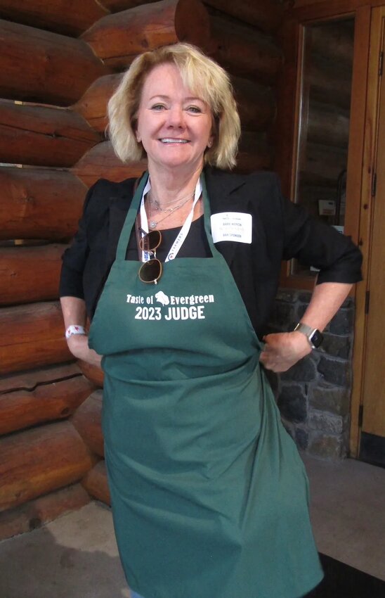 Barb Woycik with Meadow Creek Design Studios dons a judge’s apron as she prepares to judge entries in Taste of Evergreen.